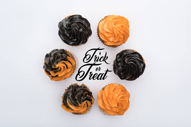 top view of delicious Halloween cupcakes in circle with trick or treat illustration isolated on white - Photo, Image