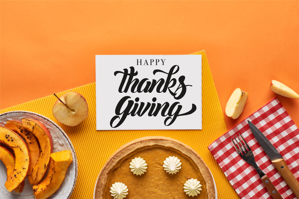 vrchní pohled na lahodný dýňový koláč v blízkosti karty se šťastným díkůvzdání ilustrace na oranžovém pozadí s jablky - Fotografie, Obrázek