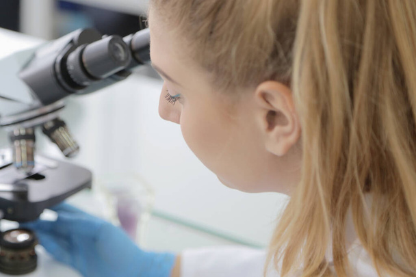 Jeune scientifique femelle regardant à travers un microscope dans une la - Photo, image