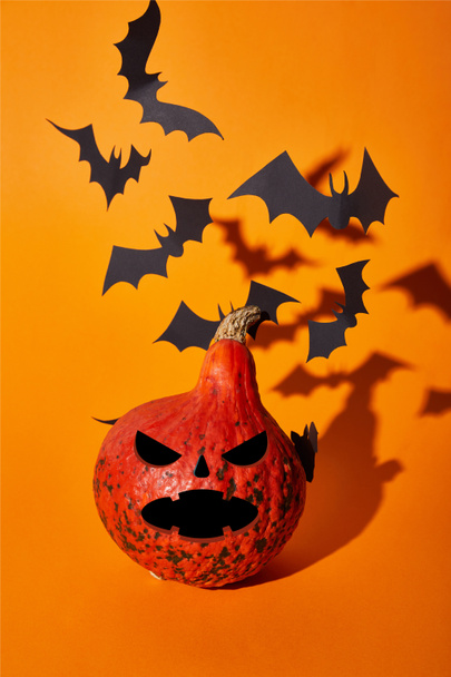 spooky pumpkin and paper bats with shadow on orange background, Halloween decoration - Photo, Image