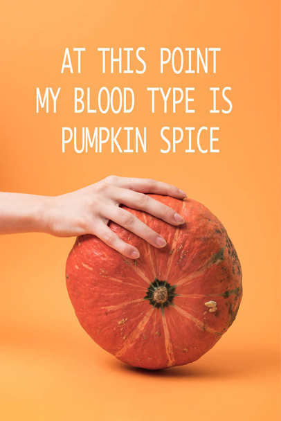 partial view of woman touching pumpkin on orange background with at this point my blood type is pumpkin spice illustration - Фото, зображення