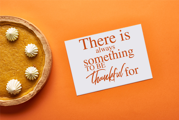top view of pumpkin pie and card with there is always something to be thankful for illustration on orange background - Photo, Image