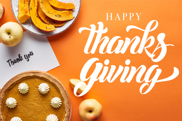 bovenaanzicht van pompoentaart, rijpe appels en dank u kaart op oranje achtergrond met vrolijke Thanksgiving illustratie - Foto, afbeelding