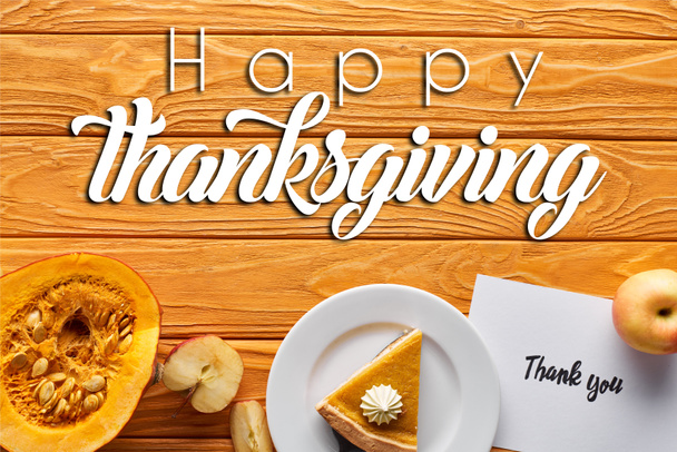 bovenaanzicht pompoentaart, rijpe appels en bedankkaart op houten tafel met vrolijke Thanksgiving illustratie - Foto, afbeelding