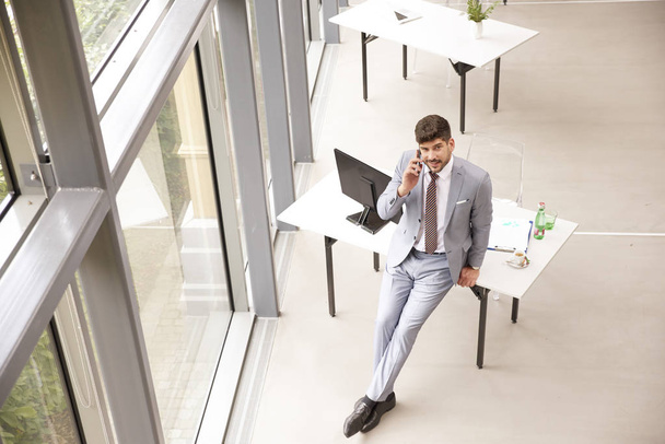 Повнометражний знімок бізнесмена, що стоїть в офісі і мак
 - Фото, зображення