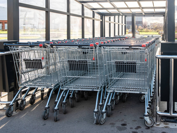 Rows of shopping trolleys with pay system. Attribute of a supermarket and a supermarket in a metropolis. - Foto, imagen