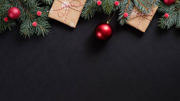 Christmas tree with red decorations and gifts on black background. Flat lay, top view, overhead. Christmas banner mockup. - Фото, изображение