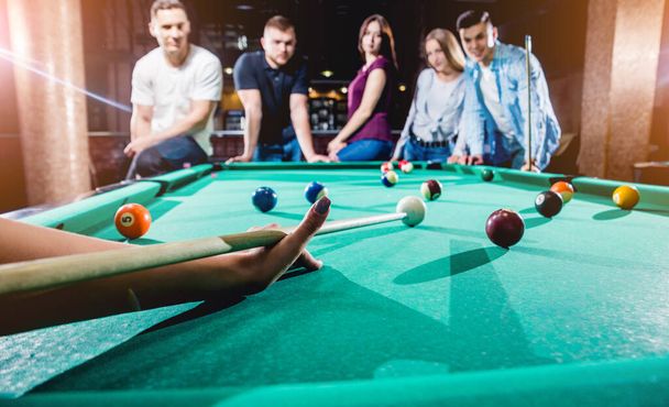 Group of young cheerful friends playing billiards. Funny time after work - Foto, imagen