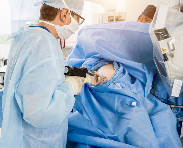 Arthroscope surgery. Orthopedic surgeons in teamwork in the operating room with modern arthroscopic tools. Hospital background - Фото, изображение