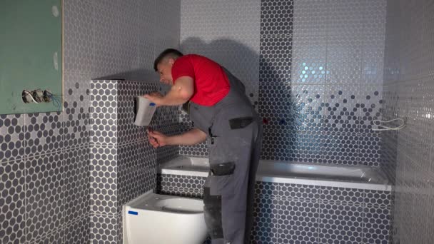 ammattitaitoinen työntekijä asentaa wc huuhtele painiketta uudessa modernissa kylpyhuoneessa
 - Materiaali, video