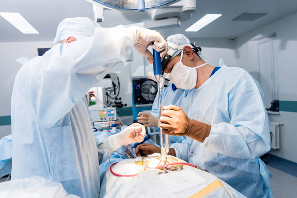 Wirbelsäulenoperationen. Gruppe von Chirurgen im Operationssaal mit Operationsausrüstung. Laminektomie. moderner medizinischer Hintergrund - Foto, Bild