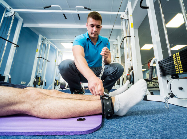 Rehabilitation therapy. Young man doing exercises on mat under supervision of physiotherapist - Foto, immagini