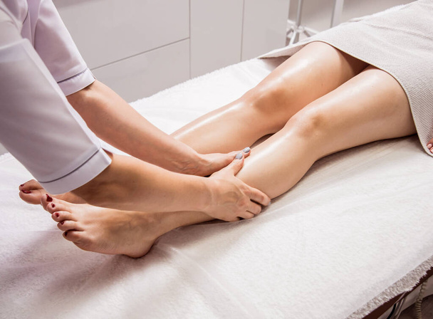 Beautiful young woman enjoying foot massage in spa salon. Cosmetology concept - Foto, Bild