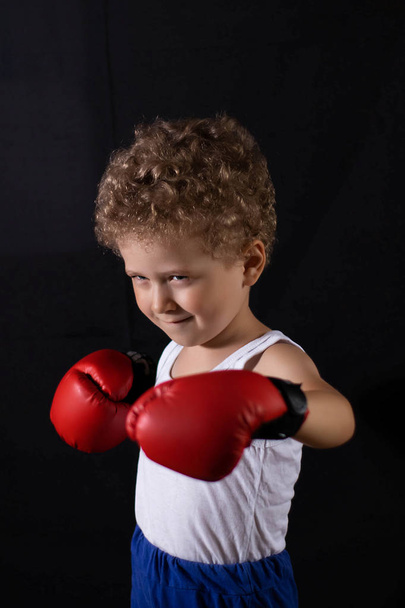 Little boy in red boxing gloves on a black background. Sports, children's boxing. - Photo, image