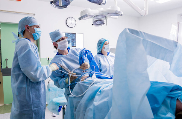 Arthroscope műtét. Ortopéd sebészek csapatmunkában a műtőben, modern artroskopikus eszközökkel. Térd műtét. Kórházi háttér - Fotó, kép