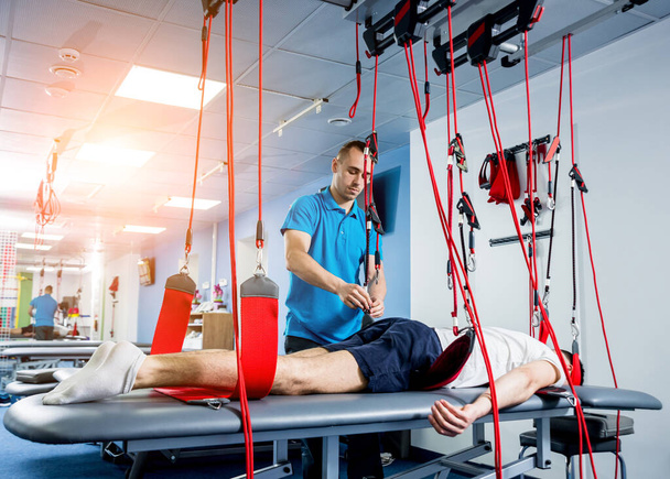 Physiotherapy. Suspension training therapy. Young man doing fitness traction therapy with suspension-based exercise training system - Φωτογραφία, εικόνα