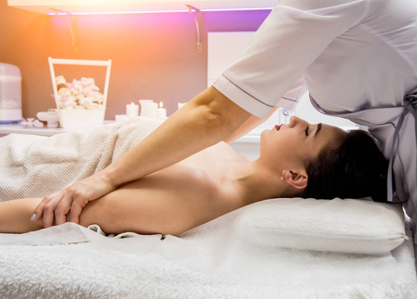 Mooie jonge vrouw geniet van massage in spa salon. Cosmetologisch concept - Foto, afbeelding