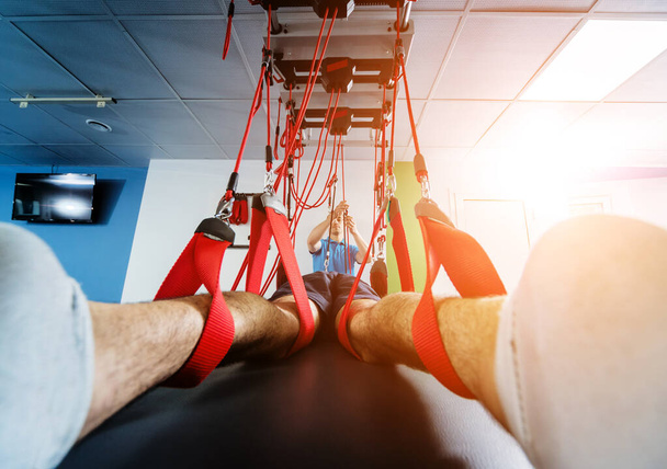 Physiotherapy. Suspension training therapy. Young man doing fitness traction therapy with suspension-based exercise training system - Foto, Bild