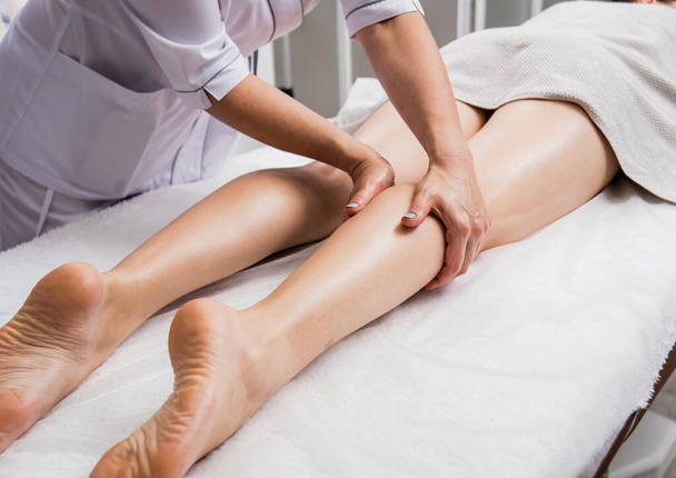 Beautiful young woman enjoying legs massage in spa salon. Cosmetology concept - Foto, afbeelding