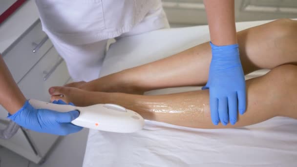 unikátní technologie v kosmetice, kosmetička provádí laserové fotoepilace na nohou pacientky v léčebně salonu krásy - Záběry, video