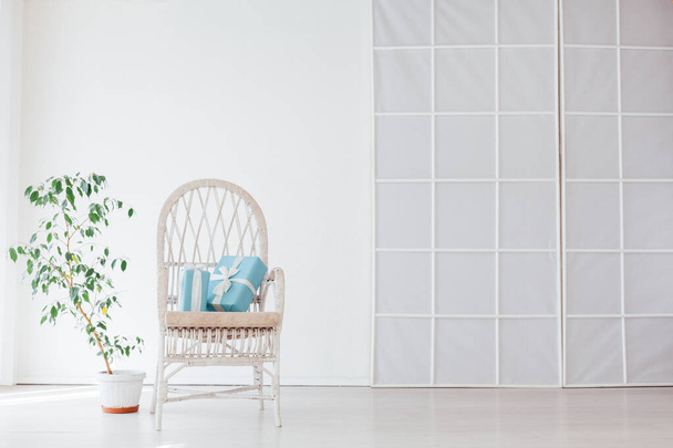 λευκή καρέκλα με δώρα στο εσωτερικό ενός λευκού άδειου δωματίου - Φωτογραφία, εικόνα
