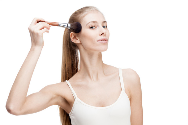 Young blond woman holding cosmetics brush on white - Фото, изображение