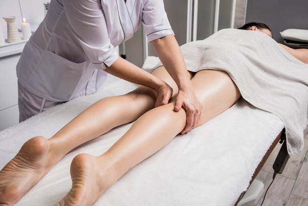 Beautiful young woman enjoying legs massage in spa salon. Cosmetology concept - Valokuva, kuva