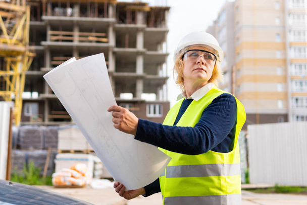 A woman Builder at a construction site inspects a house made of brick - Φωτογραφία, εικόνα