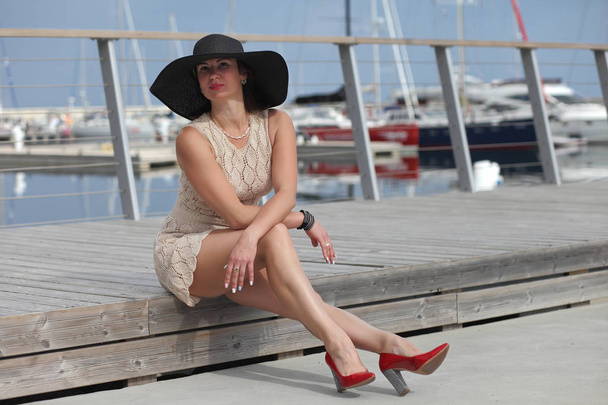 Νεαρή γυναίκα με καπέλο κοντά σε βάρκες στη μαρίνα - Φωτογραφία, εικόνα