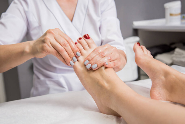 Beautiful young woman enjoying foot massage in spa salon. Cosmetology concept - Fotografie, Obrázek
