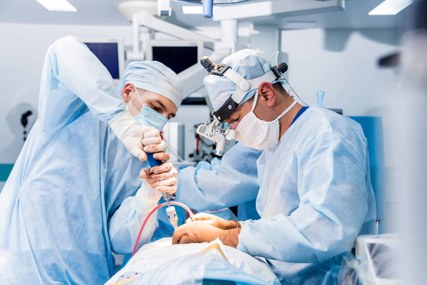Cirugía de columna. Grupo de cirujanos en quirófano con equipo quirúrgico. Laminectomía. Formación médica moderna
 - Foto, imagen