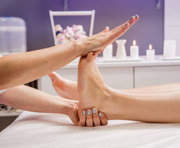 Beautiful young woman enjoying foot massage in spa salon. Cosmetology concept - Foto, Imagem