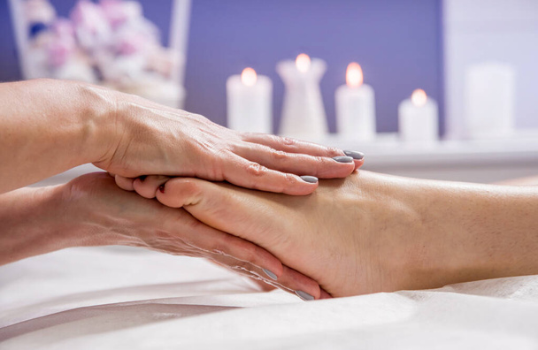 Beautiful young woman enjoying foot massage in spa salon. Cosmetology concept - Foto, imagen