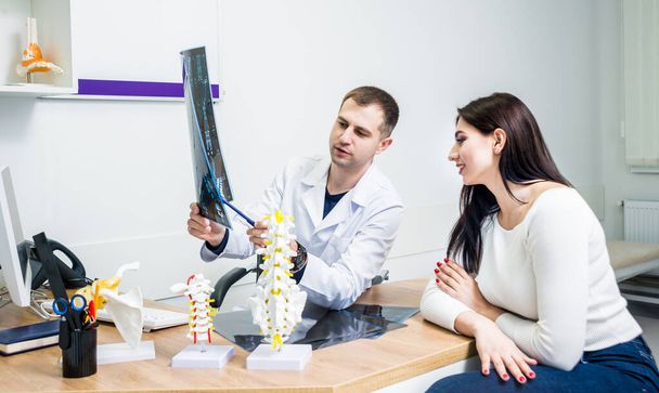 Traumatologist showing MRI film to patient in hospital. Medical background - Fotografie, Obrázek