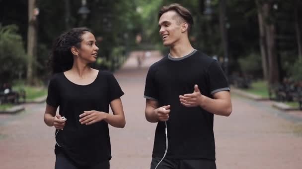 Young Man and Muslin Girl Talking Smiling and Holding Headphones in Their Hands Looking Happy Walking in the Park People Concept. - Footage, Video
