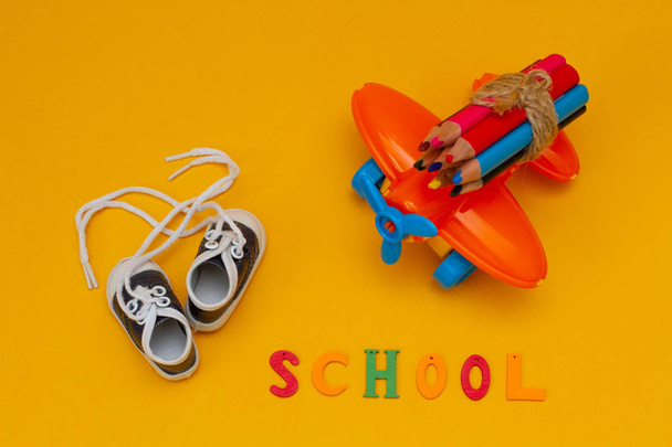 Buntstifte auf einem kleinen orangefarbenen Spielzeugflugzeug auf gelbem Hintergrund. - Foto, Bild