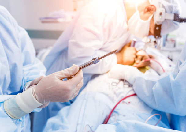 Spinal surgery. Surgeon show polyaxial screw in operating room with surgery equipment. Laminectomy. Spine fixation systems. Medical background - 写真・画像