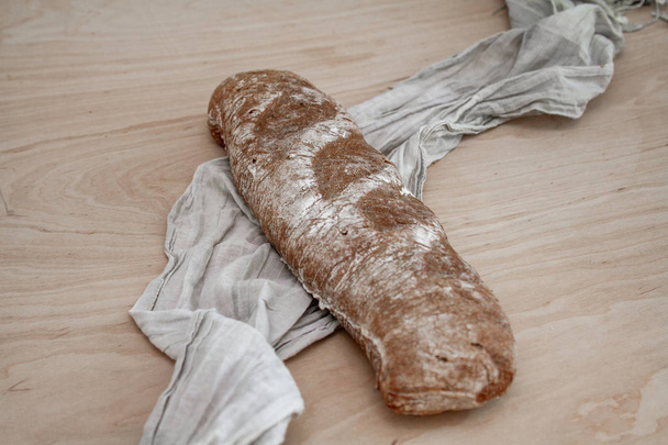 wholegrain bread loaf with fabric on wooden surface - Photo, Image