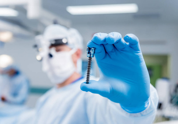 Spinal surgery. Surgeon show polyaxial screw in operating room with surgery equipment. Laminectomy. Spine fixation systems. Medical background - Foto, Bild