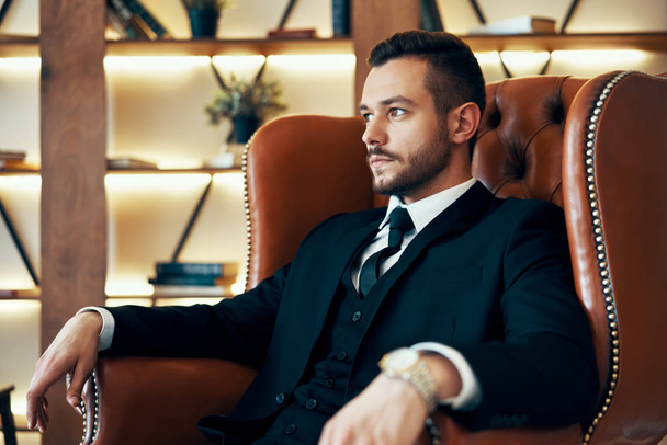 Confident young man relax in armchair in luxury interior. success and rest concept - Fotografie, Obrázek