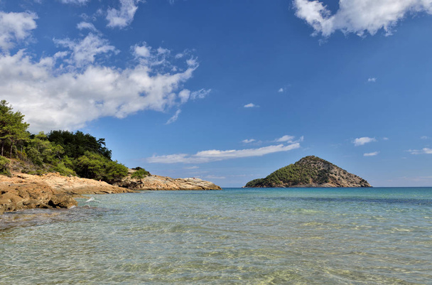Rajska plaża z błękitnymi wodami, piaskiem i wyspą na wyspie Thassos, Wschodnia Macedonia i Tracja, Grecja - Zdjęcie, obraz