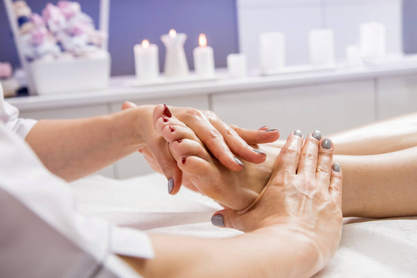 Beautiful young woman enjoying foot massage in spa salon. Cosmetology concept - Zdjęcie, obraz