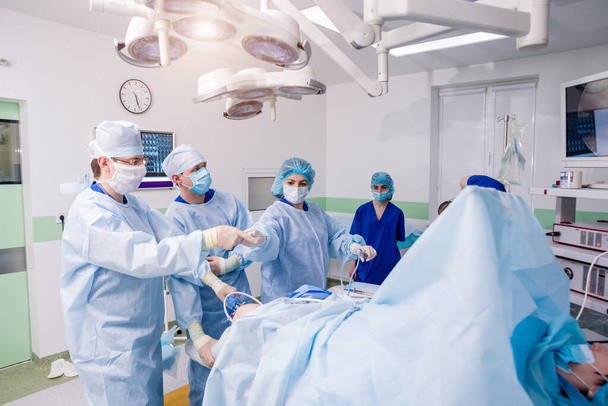 Arthroscope surgery. Orthopedic surgeons in teamwork in the operating room with modern arthroscopic tools. Knee surgery. Hospital background - 写真・画像