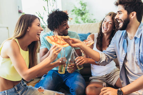 Többnemzetiségű fiatal barátok csoportja, akik otthon esznek pizzát és hav - Fotó, kép