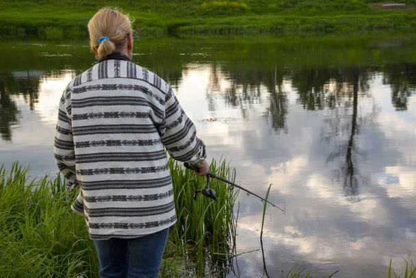 Fishing, a woman with a fishing rod stands by the river - Fotografie, Obrázek