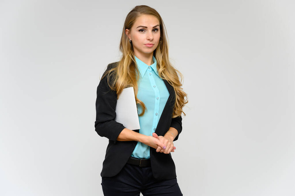 Portrait of a pretty blonde girl financial secretary with long curly hair in a business suit standing in the studio on a white background with emotions in different poses with a folder in his hands. - Foto, immagini