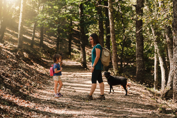 Mother and daughter walking trough a path in the woods - Фото, изображение