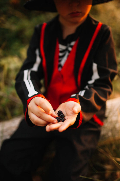 Niño disfrazado de halloween en el bosque con moras
 - Foto, imagen