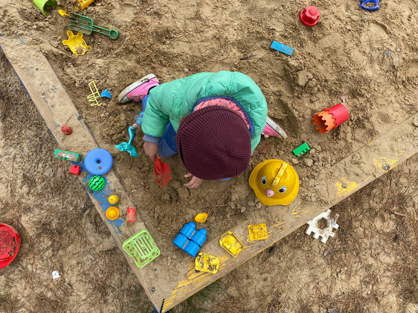 Klein mooi meisje baby spelen in de zandbak op de speelplaats. - Foto, afbeelding