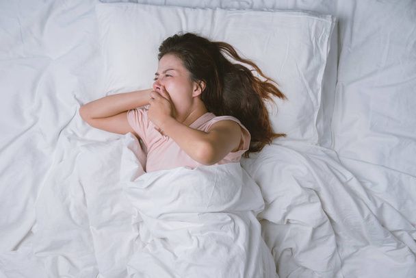 Teenage girl sleeping resting. good night sleep concept. Girl wearing a pajama sleep on a bed in a white room in the morning. warm tone. - Photo, Image